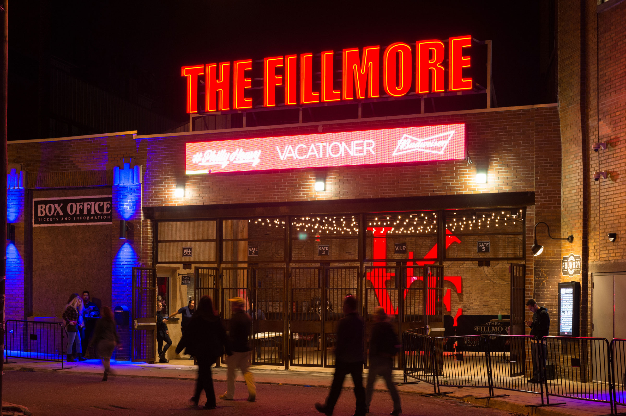 Night view of The Fillmore entrance with a bright red marquee. People walk by under warm lights, creating a lively, inviting atmosphere.